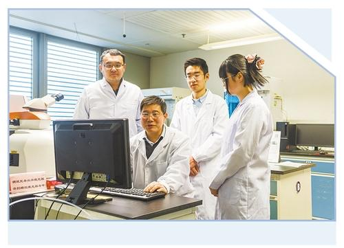 在清华大学的实验室中，李俊华（前中）与学生们一起研讨科研项目。（资料照片）